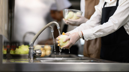 Female student washing vegetables during cooking class.の写真素材