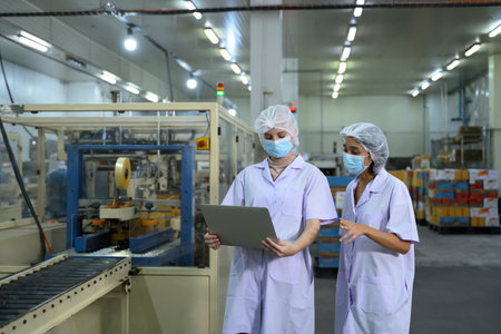 Food factory staff reviewing production data in a food packaging facility.の写真素材