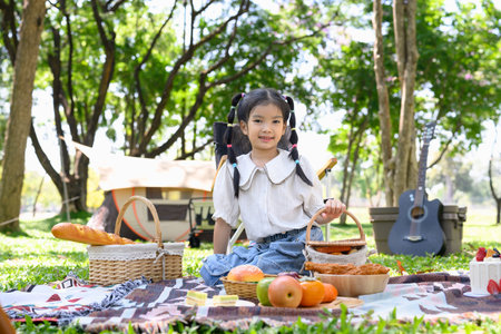 Cute little girl at a family camping picnic with picnic baskets and fresh food.の写真素材