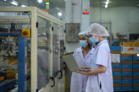Factory workers overseeing automated packaging equipment.