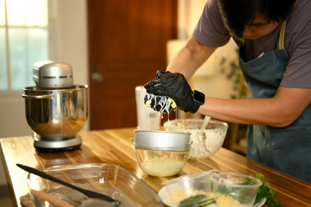 Close up of hands in gloves pressing butter to separate out liquid buttermilk.の写真素材