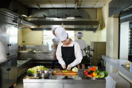 Culinary student practices chopping vegetables during a hands on cooking class in a kitchen.の写真素材