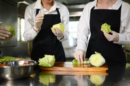 Young chefs practice slicing vegetables during a hands on cooking class at culinary school.の写真素材