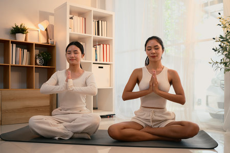 Calm and focused mother and daughter practicing yoga together in a peaceful indoor.の写真素材