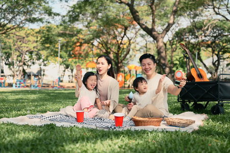 Happy family having a picnic and playing with bubbles together at the park.の写真素材