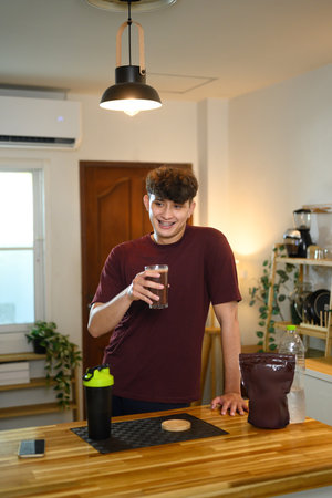 Smiling male holding a glass of chocolate protein drink after exercise.の写真素材