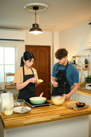 Couple enjoying morning cooking time, preparing pancake batter together in kitchen.の写真素材