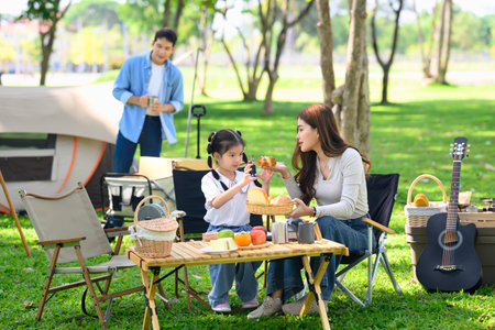 Mother and daughter enjoying a relaxing breakfast at a campsite.の写真素材