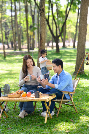 Cheerful parents enjoying a warm drink together at campsite.の写真素材