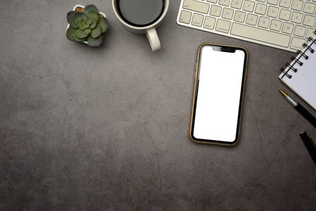 Flat lay of smartphone with blank screen on dark modern desk.の写真素材