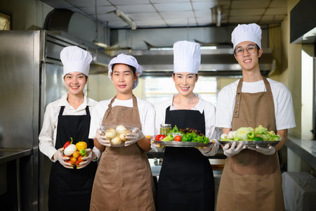 Group of culinary students proudly holding fresh vegetables, ready for their cooking class.の写真素材