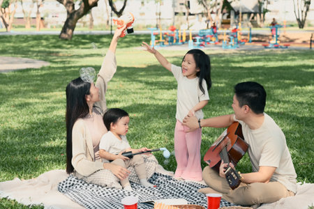 Happy family playing with bubbles during a picnic in the park.の写真素材