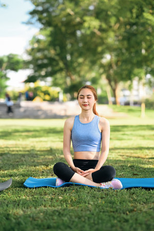 Woman practicing meditation and deep breathing on a yoga mat in a natural environment.の写真素材
