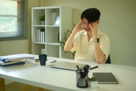 Stressed young man overwhelmed with work at home office.の写真素材