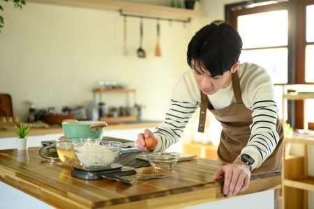 Happy Asian man cooking at home with fresh ingredients.の写真素材