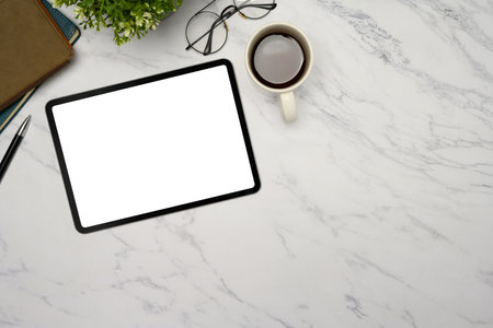 Top view of digital tablet, coffee cup, and office accessories on a marble desk.の写真素材
