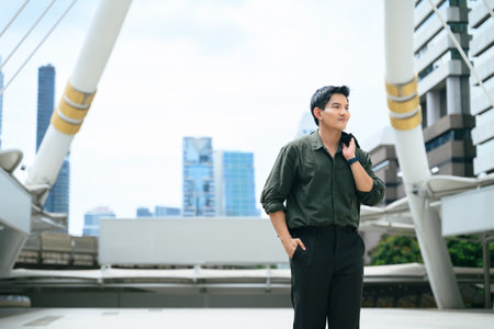 Confident young businessman walking outdoors with a jacket over his shoulder.の写真素材