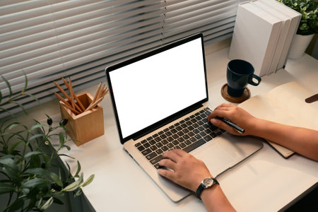 Close up of hands using a laptop with blank screen at a tidy desk.の写真素材