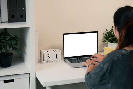 Rear view of young woman working on a laptop at a minimalist desk.の写真素材
