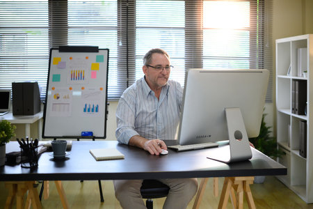 Experienced mature businessman working on computer in a contemporary office.の写真素材