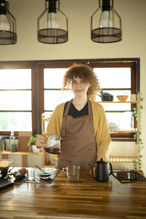 Calm young woman making a fresh cup of coffee using pour-over method.の写真素材
