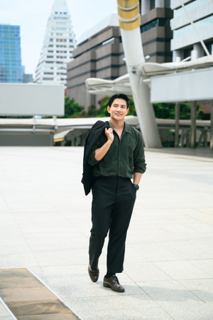 Handsome businessman walking confidently through a modern cityscape.の写真素材