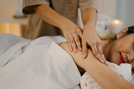 Closeup relaxed woman lying on massage table while massage therapist massages her.の写真素材