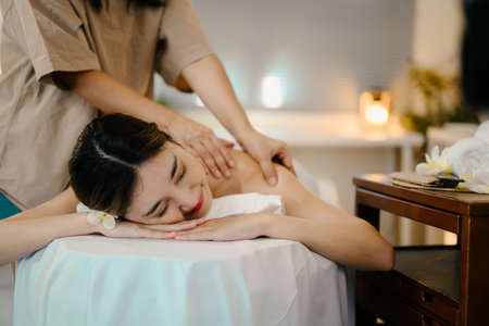 Relaxed woman lying on massage table while massage therapist massages her. Wellness concept.の写真素材