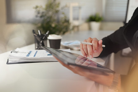 Close up of businessman using digital tablet with stylus pen at office desk.の写真素材