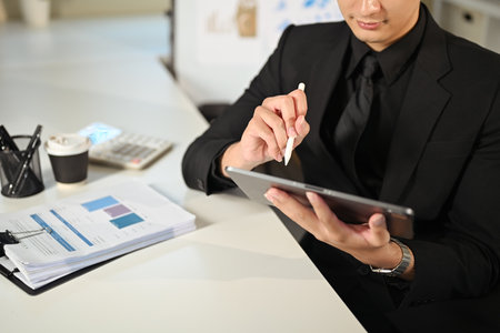 Professional businessman working on digital tablet while reviewing financial documents.の写真素材