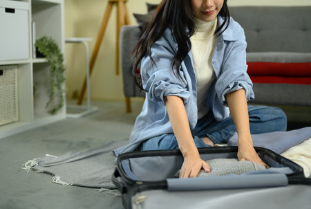 Female traveler organizing and packing luggage, getting ready for vacation trip.の写真素材