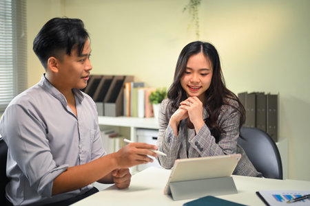 Two colleagues working together in office, discussing ideas while looking at digital tablet.の写真素材