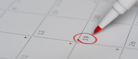 A red pen circling the 19th on a calendar, representing an appointment or reminder for an important event.の写真素材