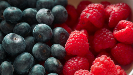 Fresh blueberries and raspberries close up, natural lighting highlighting texture and color.