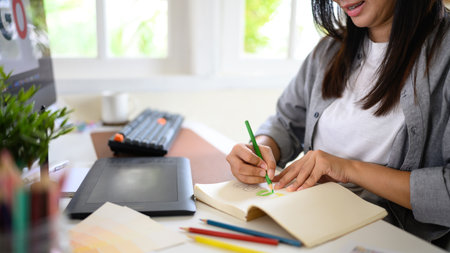 Creative woman planning logo design using traditional sketching methods alongside digital tool.