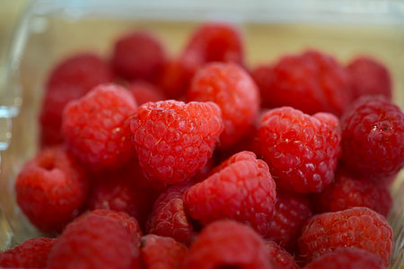 Macro shot of red raspberries showing juicy texture and natural freshness. Healthy food and...
