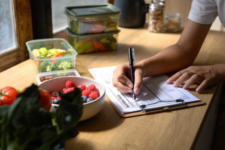 Nutritionist writing meal plan and nutrition facts on a clipboard with fresh fruits.の写真素材