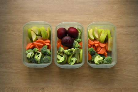Flat lay of healthy weekly meal prep in plastic containers on wooden kitchen counter.の写真素材