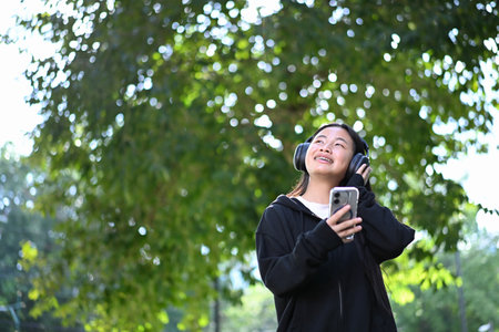 Cheerful high school student listening to songs on smartphone during break time.の写真素材