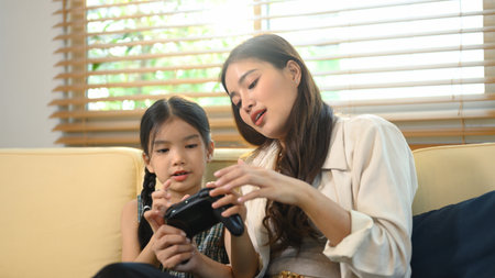 Parent and daughter spending quality time together, learning and playing video games.の写真素材