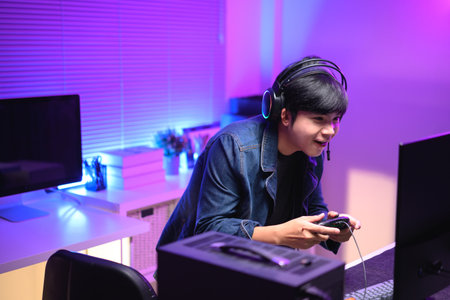 A young man enjoying playing computer games in a neon-lit room. The gaming atmosphere features vibrant colors.の写真素材