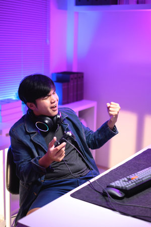 A young man enjoying playing computer games in a neon-lit room. The gaming atmosphere features vibrant colors.の写真素材