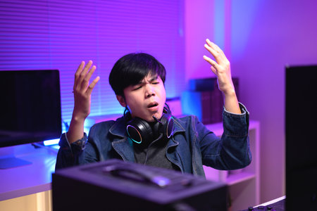 A young man enjoying playing computer games in a neon-lit room. The gaming atmosphere features vibrant colors.の写真素材