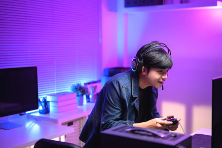 A young man enjoying playing computer games in a neon-lit room. The gaming atmosphere features vibrant colors.の写真素材