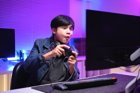 A young man enjoying playing computer games in a neon-lit room. The gaming atmosphere features vibrant colors.の写真素材