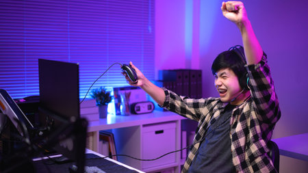 Excited gamer celebrating victory after winning video game at night,.