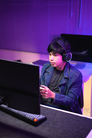 Focused gamer playing video game at night time.の写真素材
