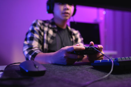 Closeup man playing video game at night with headset and neon RGB lighting.の写真素材