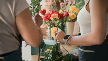 Closeup people learning to arrange flowers in a creative workshop, crafting colorful bouquets with teamwork.の写真素材