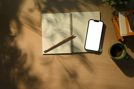 Smartphone with blank screen, notebook, coffee cup and on table. Top view, flat lay.の写真素材